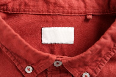 Photo of Blank clothing label on red shirt, top view