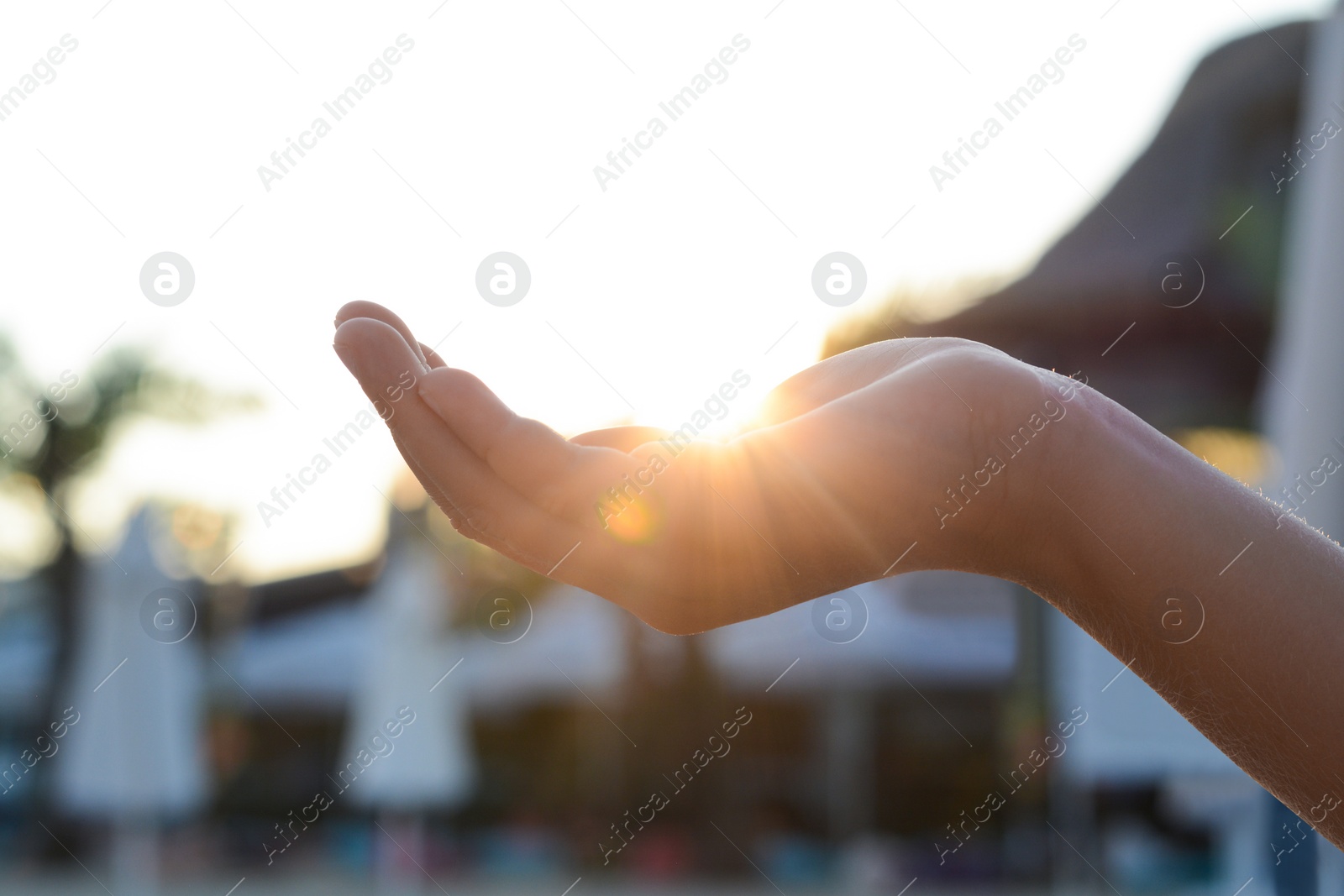 Photo of Girl holding her hand against sunlight on beach, closeup