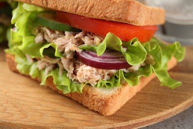 Delicious sandwich with tuna and vegetables on wooden board, closeup