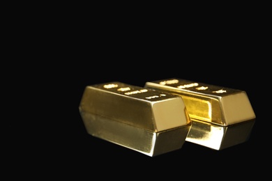 Photo of Precious shiny gold bars on black background