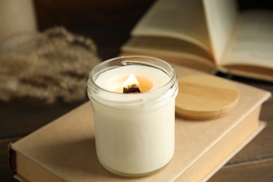 Photo of Beautiful candle with wooden wick on book