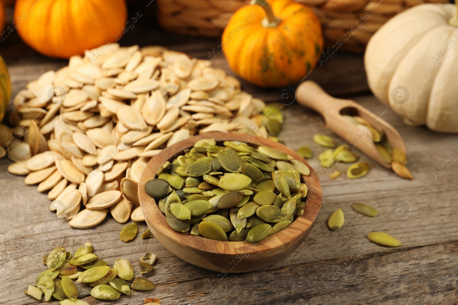 Photo of Seeds and fresh pumpkins on wooden table