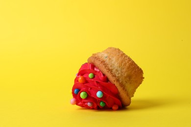 Photo of Dropped cupcake with cream on yellow background