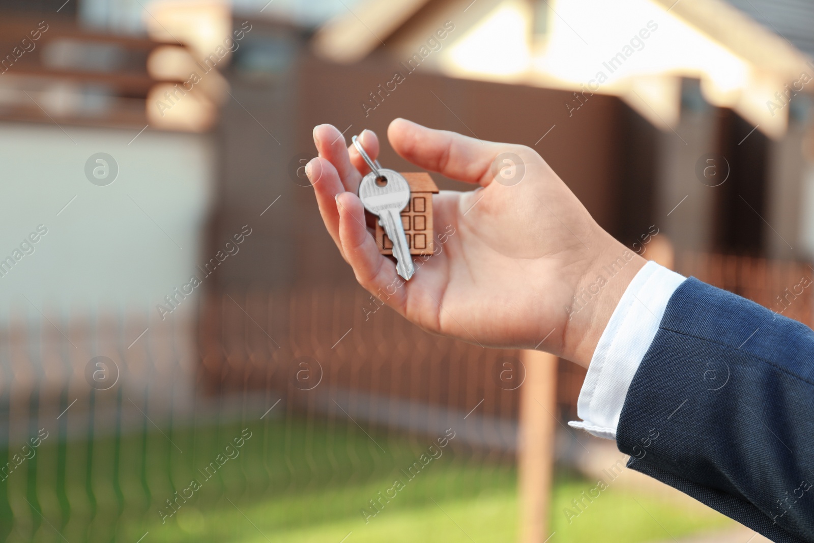 Photo of Real estate agent holding key outdoors, closeup