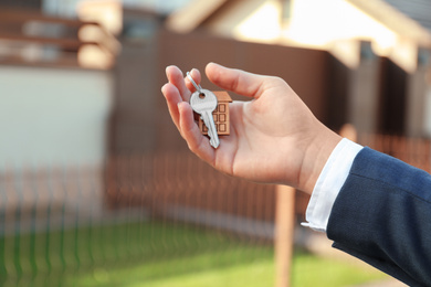 Photo of Real estate agent holding key outdoors, closeup