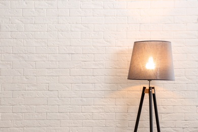 Modern floor lamp against brick wall. Space for text