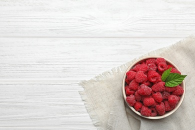 Bowl with delicious ripe raspberries on white wooden table, top view. Space for text