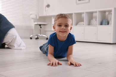 Photo of Cute little boy lying on warm floor at home. Heating system