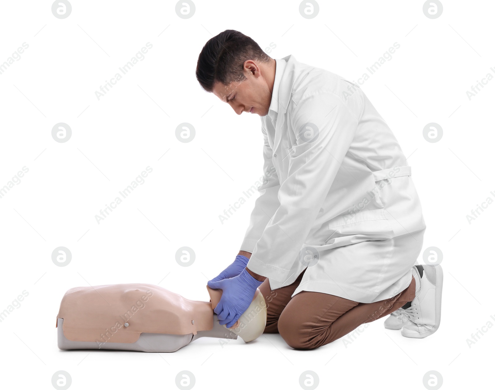 Photo of Doctor in uniform practicing first aid on mannequin against white background