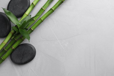 Photo of Spa stones and bamboo on light grey table, flat lay. Space for text