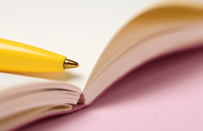 Photo of Ballpoint pen and notebook on pink background, closeup. Space for text