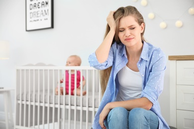 Photo of Young mother suffering from postnatal depression and little baby in room