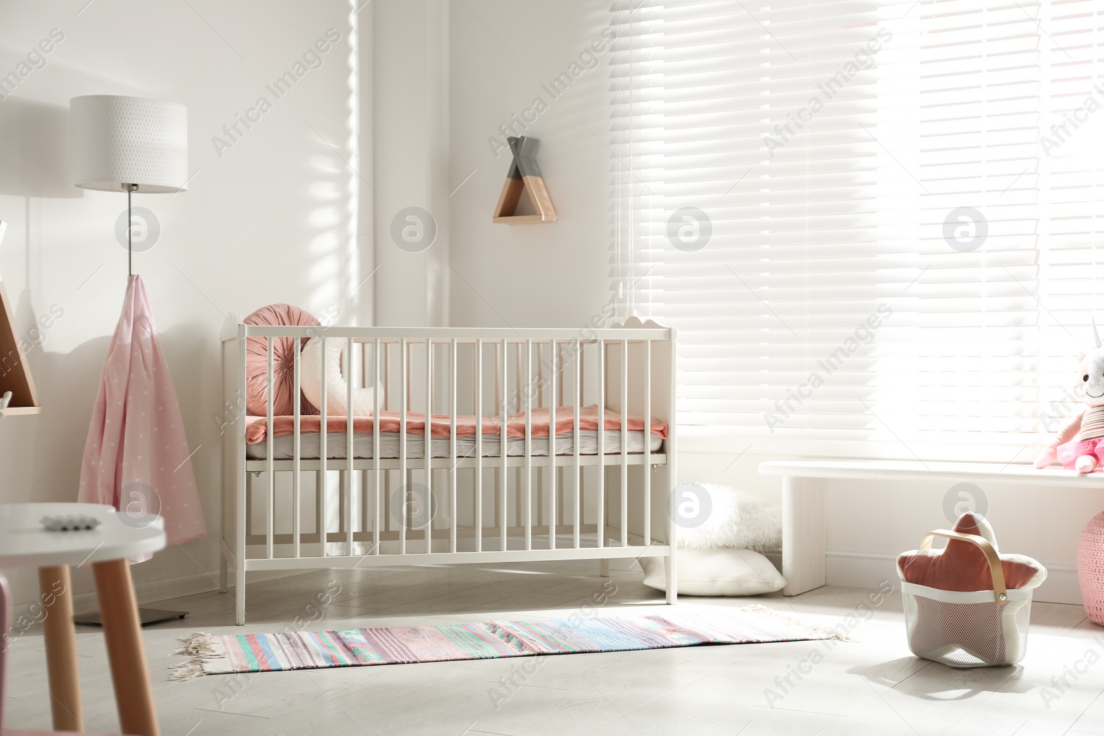 Photo of Cute baby room interior with crib and decor elements