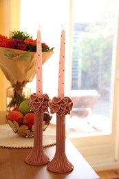 Photo of Bouquet of flowers, bowl with fresh fruits and candles on wooden table indoors, selective focus