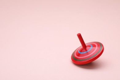 Photo of One bright spinning top on beige background, space for text. Toy whirligig