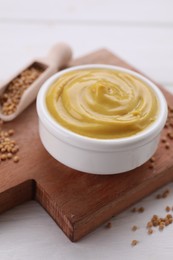 Photo of Bowl with delicious mustard and seeds on white wooden table