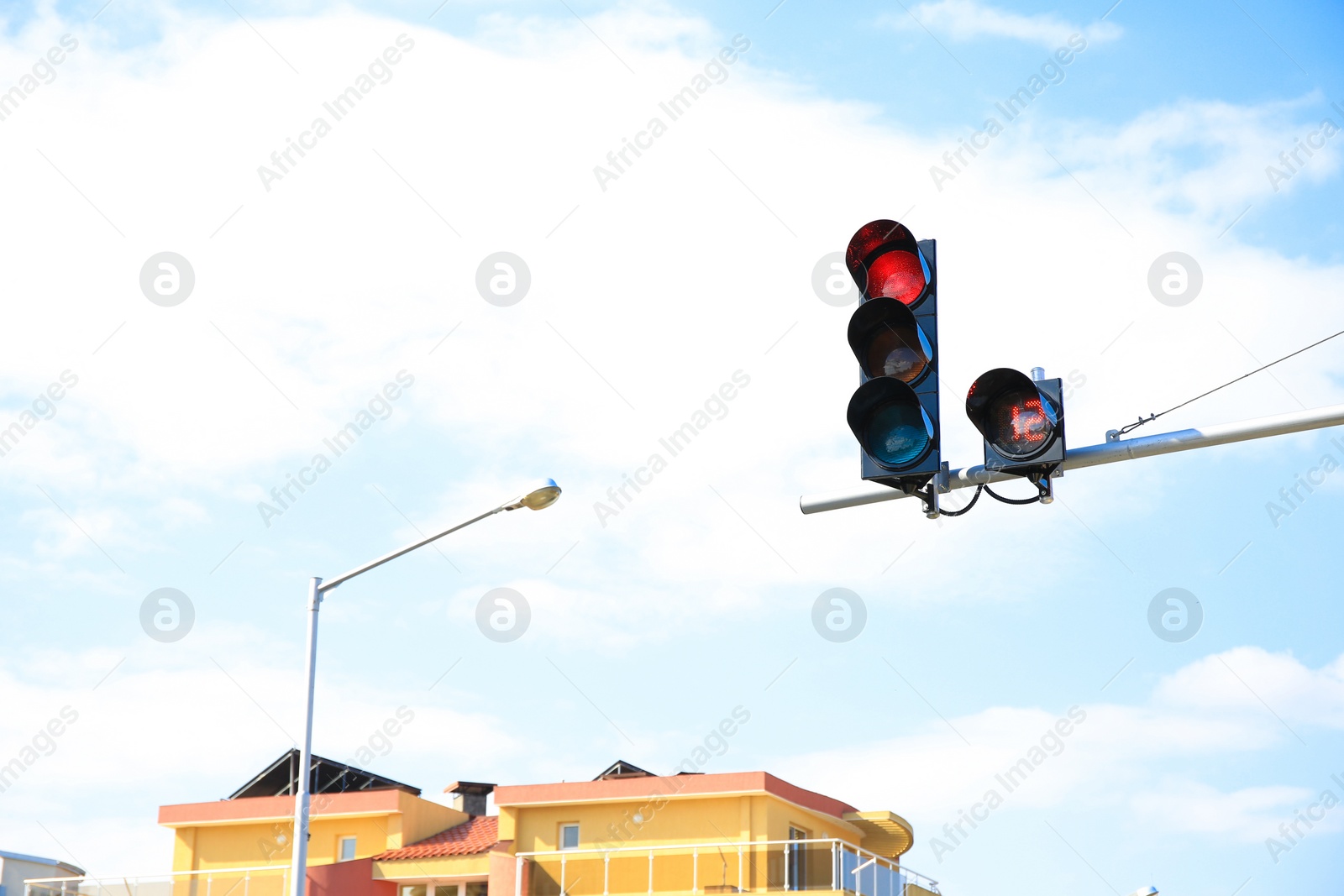 Photo of Traffic light with red sign against cloudy sky in city. Space for text