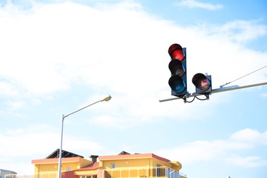 Traffic light with red sign against cloudy sky in city. Space for text