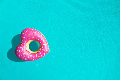 Heart shaped inflatable ring floating in swimming pool, top view with space for text. Summer vacation