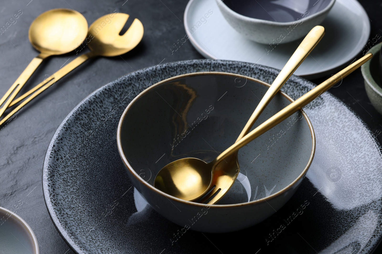 Photo of Set of clean tableware on black table, closeup