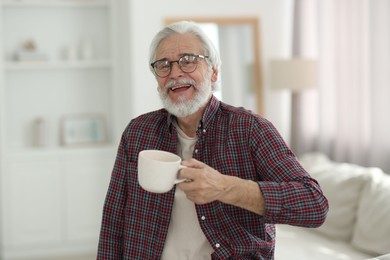 Photo of Portrait of happy grandpa with glasses and cup of drink indoors
