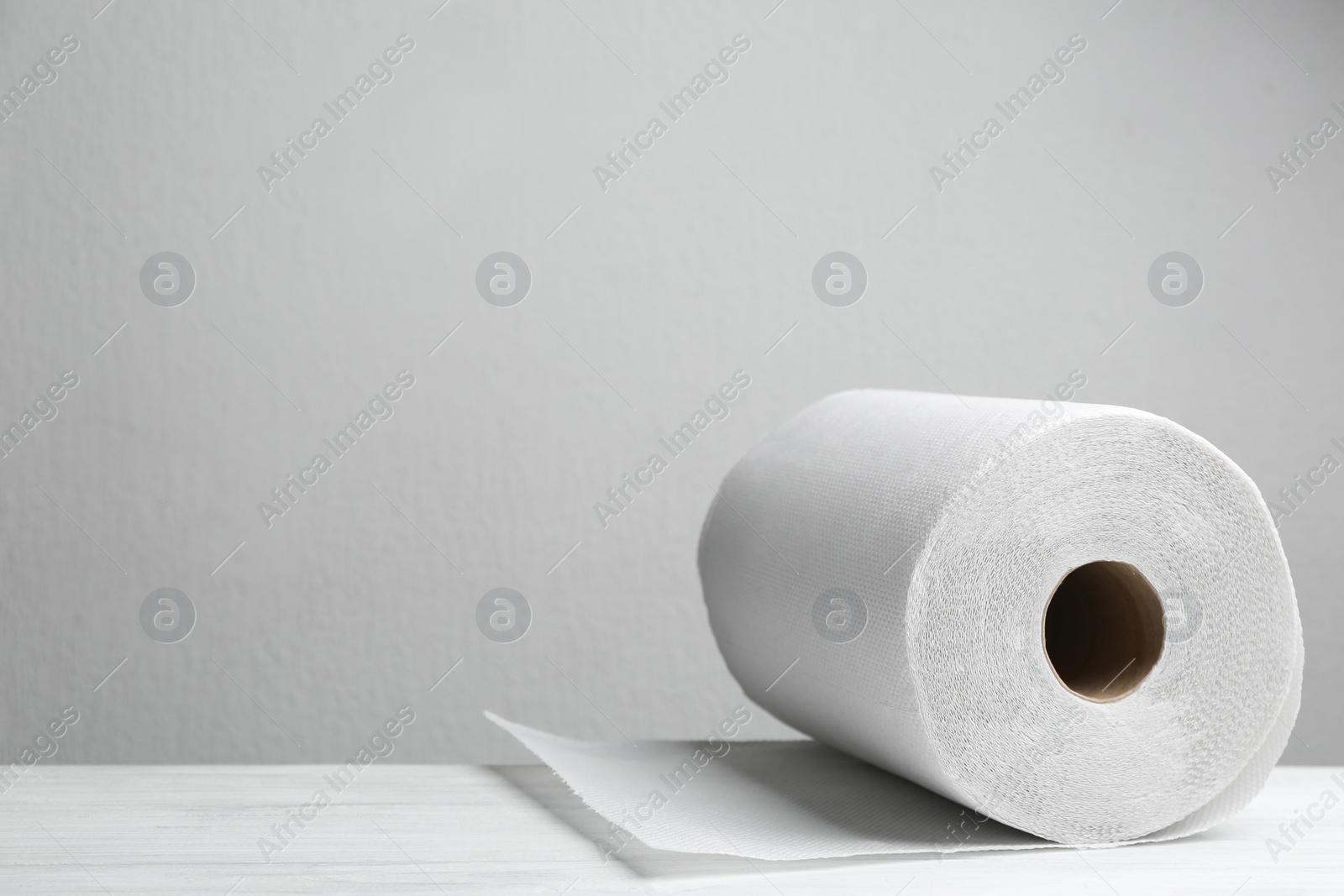 Photo of Roll of paper towels on white wooden table, space for text