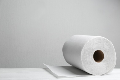 Roll of paper towels on white wooden table, space for text