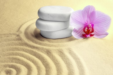 Stack of white stones and beautiful flower on sand with pattern. Zen, meditation, harmony