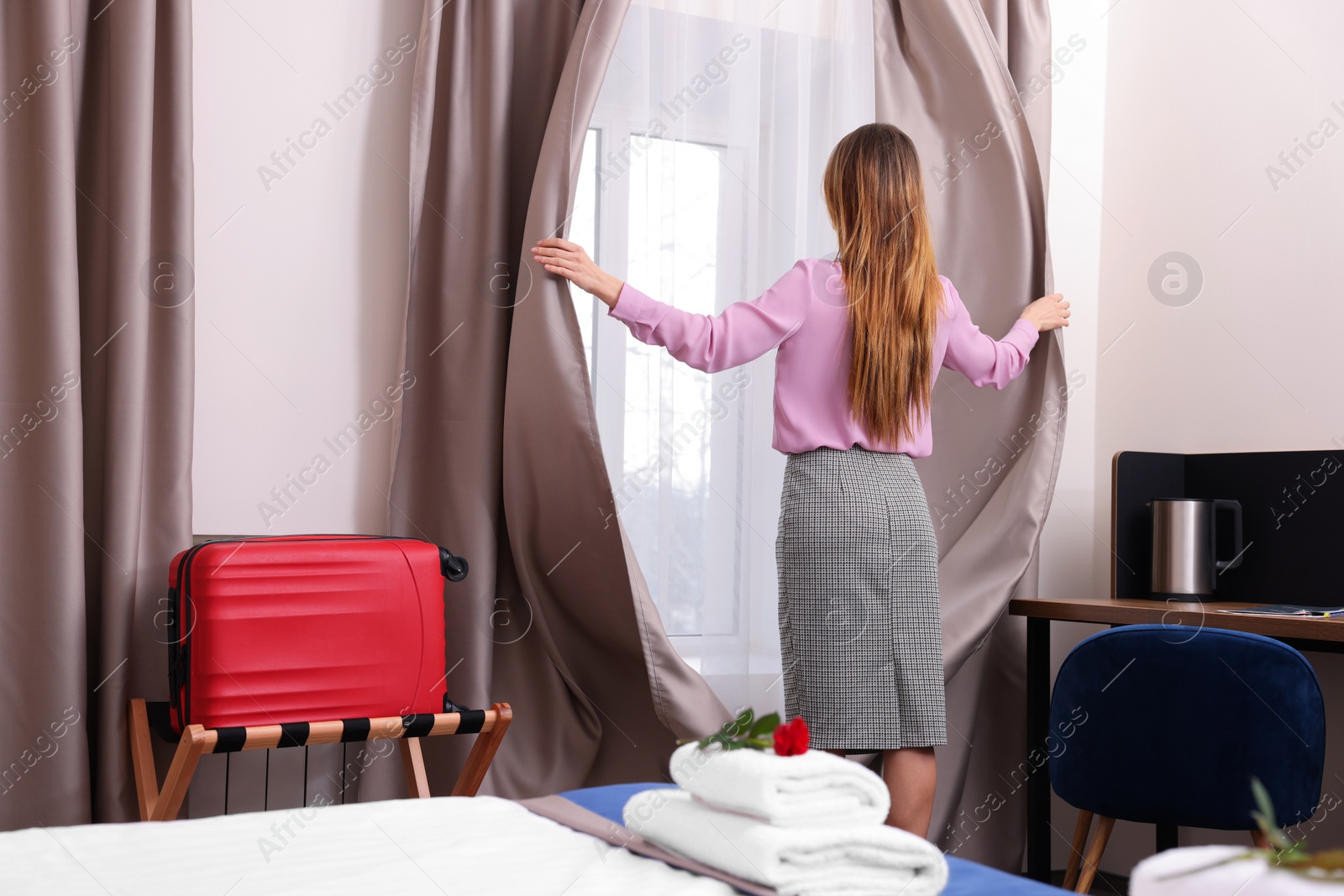 Photo of Beautiful businesswoman opening window curtains in hotel room