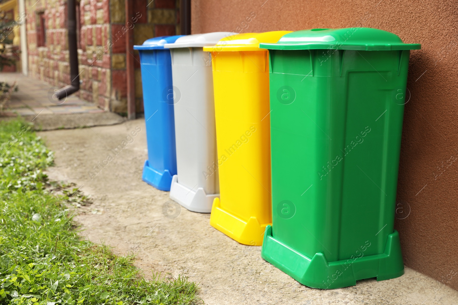 Photo of Many colorful recycling bins near brown wall outdoors