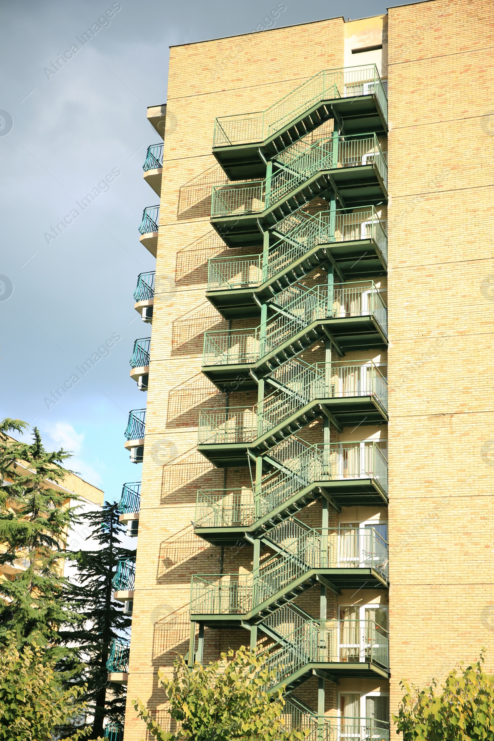 Photo of View of modern metal empty fire escape ladder near building on sunny day outdoors