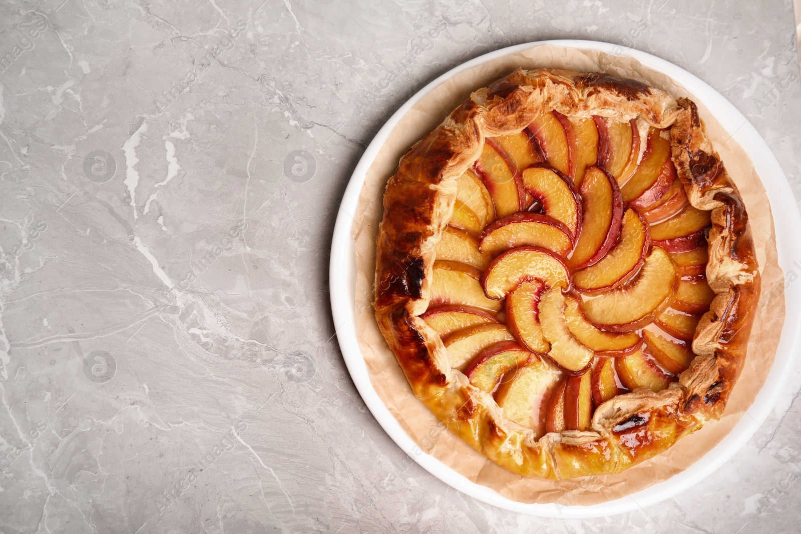 Photo of Delicious fresh peach pie on grey table, top view. Space for text