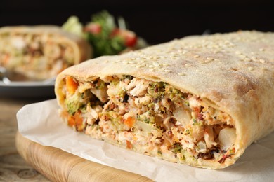Photo of Tasty strudel with chicken and vegetables on wooden table, closeup