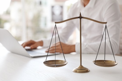 Photo of Scales of justice and blurred notary with laptop on background