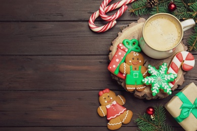 Photo of Decorated Christmas cookies and cup of delicious drink on wooden table, flat lay. Space for text