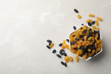 Photo of Bowl of raisins on grey background, top view with space for text. Dried fruit as healthy snack