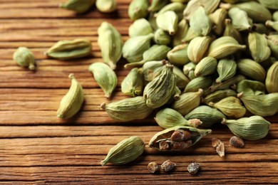 Pile of dry cardamom pods on wooden table, closeup