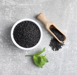 Photo of Black sesame seeds and green leaf on grey table, flat lay