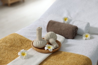 Photo of Herbal bags, flowers and towels on massage table in spa