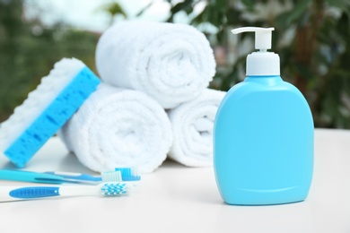 Soap dispenser and bathroom essentials on table against blurred background