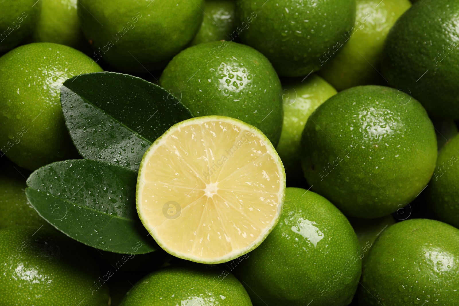 Photo of Fresh limes and leaves with water drops as background, top view