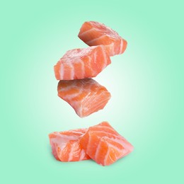Image of Pieces of salmon falling on aquamarine background