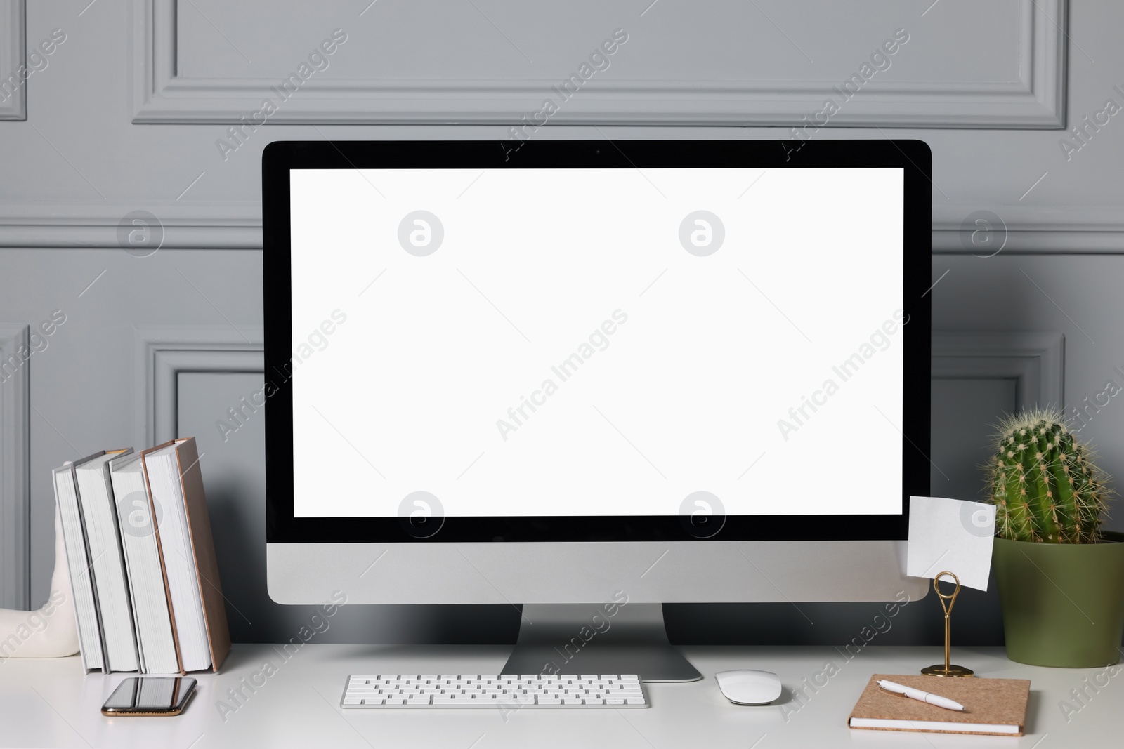 Photo of Cozy workspace with computer, cactus, smartphone and stationery on white desk