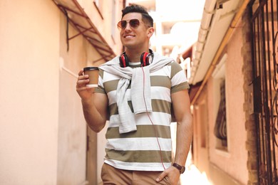 Photo of Happy man with coffee on city street in morning