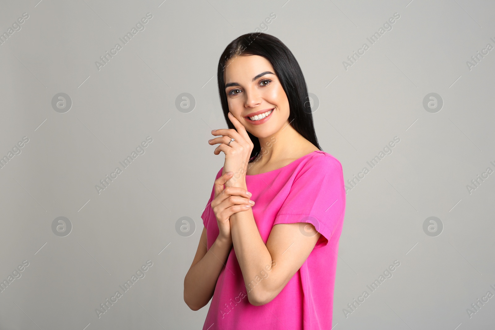 Photo of Happy young woman wearing beautiful engagement ring on grey background