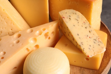 Photo of Different kinds of tasty cheese on wooden plate, closeup