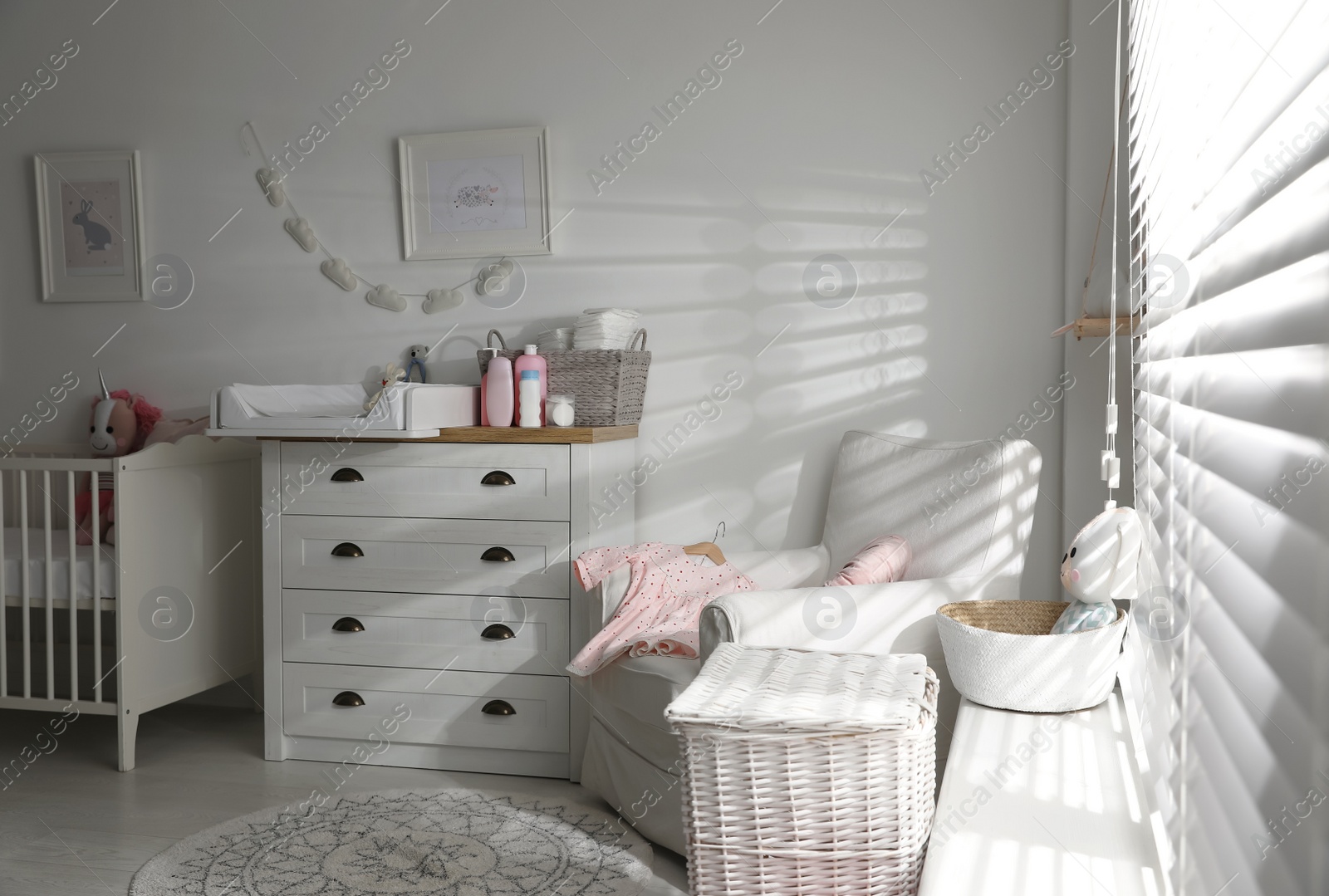 Photo of Chest of drawers with changing tray and pad in baby room. Interior design