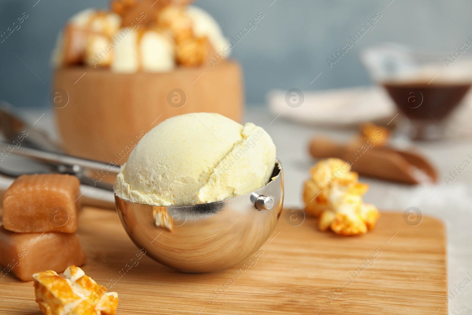 Photo of Delicious ice cream in scoop, popcorn and caramel on wooden board. Space for text