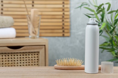 Dry shampoo spray and hairbrush on wooden table in bathroom. Space for text