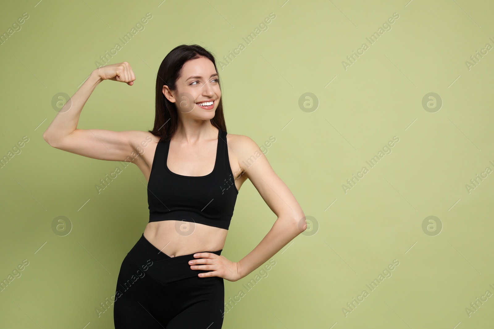 Photo of Happy young woman with slim body showing her muscles on green background, space for text